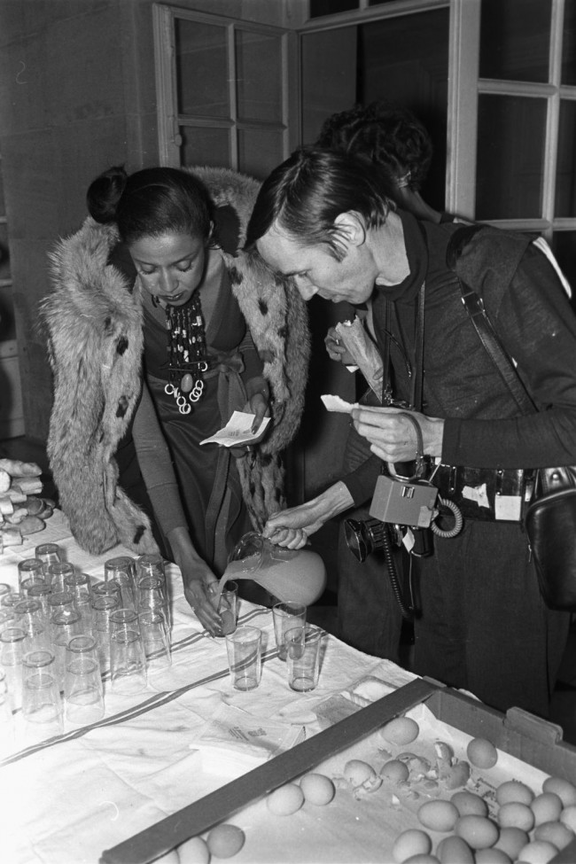 Outtake; Photographer Bill Cunningham pouring a drink for a model backstage during the fashion show to benefit the restoration of the Chateau of Versailles, five American designers matching talents with five French couturiers at the Versailles Palace on November 28, 1973 in Versailles, France. Article title: "One night and pouf! It's gone!"